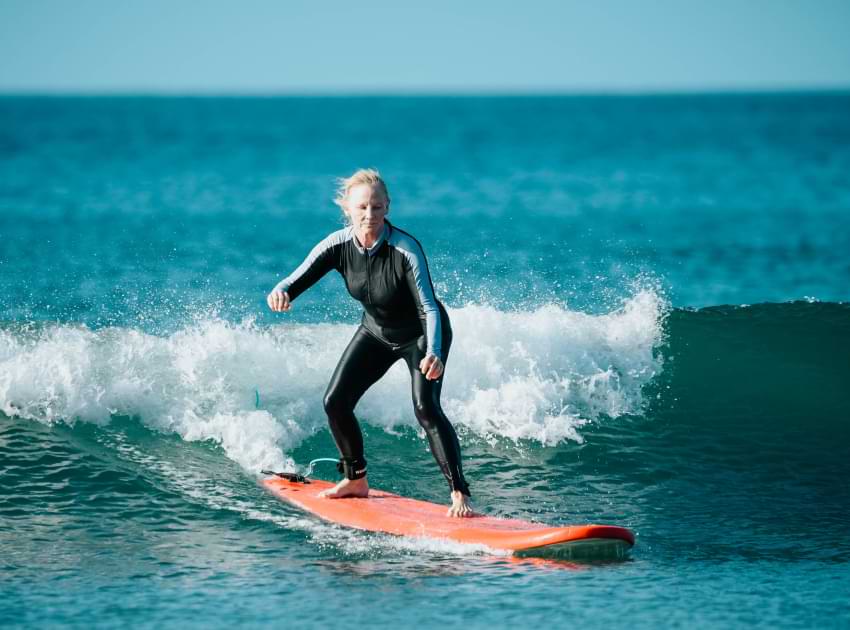 Una señora mayor surfeando las olas.